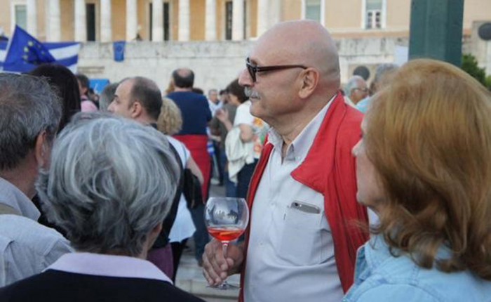  22 Ιουνίου 2015. Ο αρχιτέκτονας – ξυλουργός Δημήτρης Βαμβακάρης απαθανατίζεται με ένα ποτήρι κρασί στην πλατεία Συντάγματος στη διαδήλωση του «Μένουμε Ευρώπη» και η φωτογραφία του κάνει άμεσα τον γύρο των κοινωνικών δικτύων.