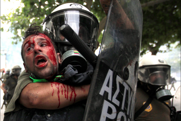 29 Ιουνίου 2011. Ανδρας των ΜΑΤ κάνει κεφαλοκλίδωμα σε αιματοβαμένο διαδηλωτή. Στη διάρκεια αυτών των 8 ετών, ήταν αμέτρητες οι συγκρούσεις της αστυνομίας με τους πολίτες. 